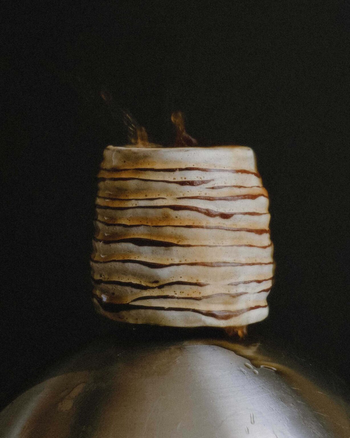 Hand-crafted Ondou Kurinuki Cup Nº5 with coffee splashing from it in a dark background and vintage effect lighting