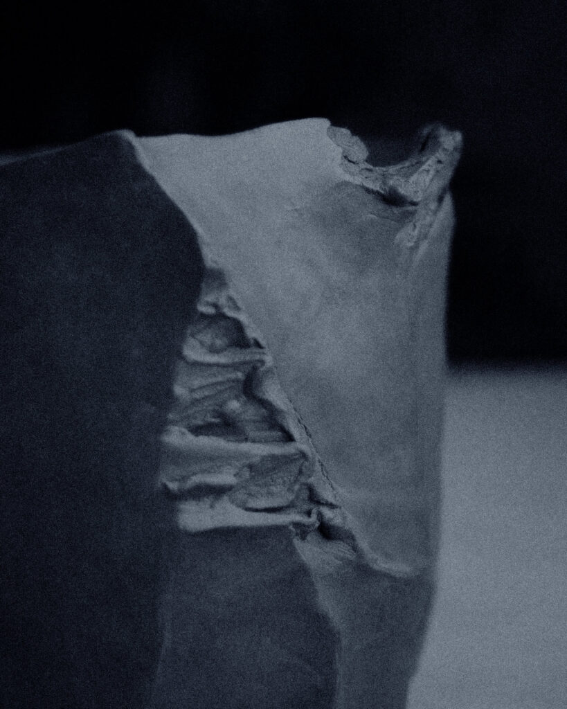 Extreme close-up of torn clay rim — layered edges created during kurinuki hand-carving process