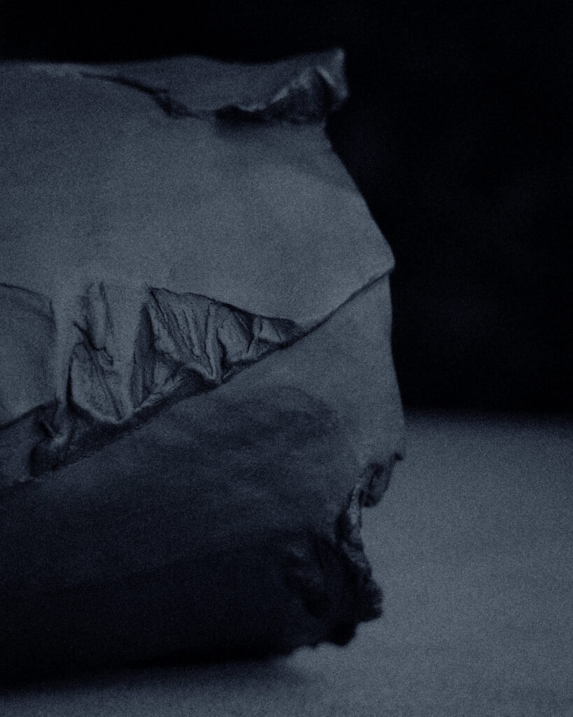 Detail of exterior surface where carved planes meet — tactile texture of unglazed black stoneware
